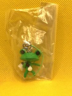 a green frog keychain sitting on top of a plastic bag