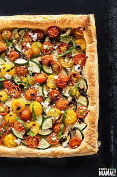 a square pizza with tomatoes, zucchini and other toppings on the top