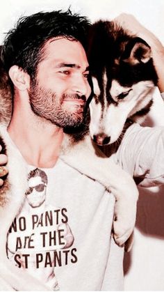 a man holding two husky dogs in his arms