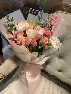 a bouquet of flowers sitting on top of a white chair next to a card holder