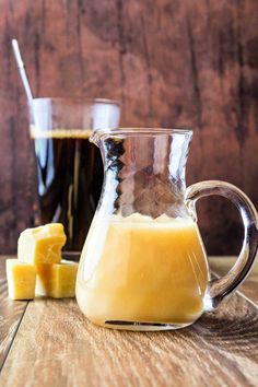 a pitcher filled with liquid sitting on top of a table next to sliced pineapple