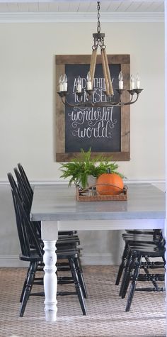 a dining room table with chairs and a chalkboard on the wall