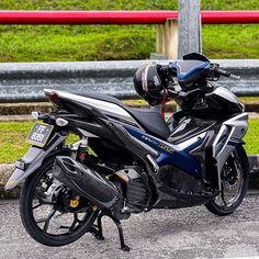 the motorcycle is parked on the side of the road near a fence and red railing