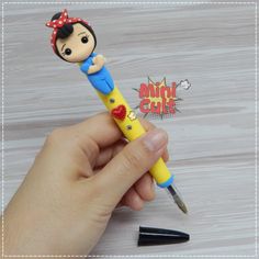 a hand holding a yellow pen with a cartoon character on it