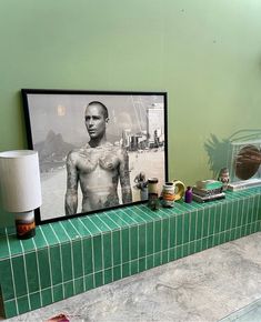 there is a framed photo on the wall next to a tiled counter with various items