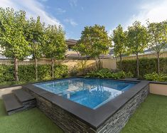 an outdoor swimming pool in the middle of a yard with grass and trees around it