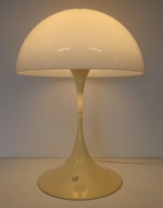 a white table lamp sitting on top of a counter next to a light bulb in the shape of a mushroom