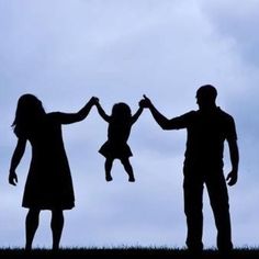 two adults and a child holding hands in the air