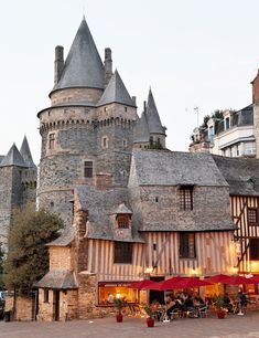 an old castle like building with lots of windows and people sitting at tables in front of it