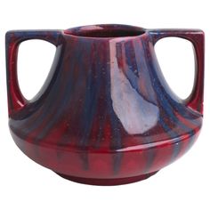 a red and blue vase is sitting on a white surface