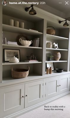 a white bookcase filled with lots of books next to a wall mounted light fixture