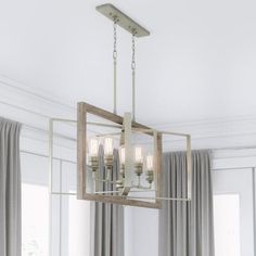 a chandelier hanging from the ceiling in a living room with curtains and drapes