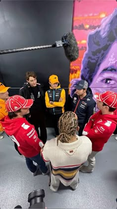 a group of people standing around each other in front of a wall with a painting on it