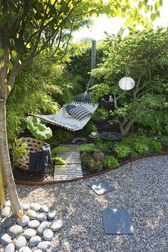 a garden with rocks, gravel and a hammock hanging from a tree in the middle