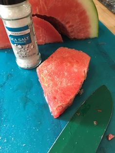 a piece of watermelon sitting on top of a cutting board next to a knife