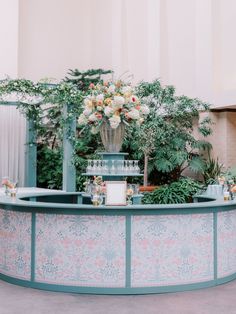 an outdoor bar with flowers and greenery on the top, surrounded by potted plants