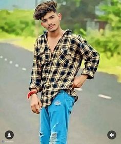 a young man standing on the side of a road with his hands in his pockets