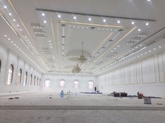 an empty room with lights on the ceiling and some workers working on the floor in front of it