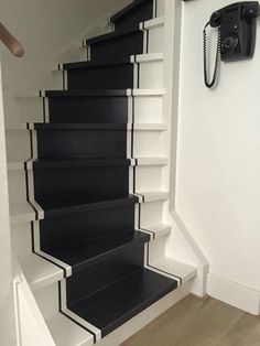 a black and white stair case next to a phone on the wall in a room