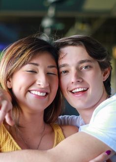 a young man and woman are hugging each other while the girl is holding her arm around him