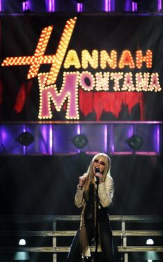 a woman standing on top of a stage in front of a cross and the words hannah montana