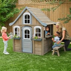 a woman and two children are playing in a small wooden house with windows on the roof