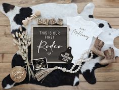 a baby announcement is displayed on a cow skin rug with its name and other items