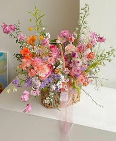 a basket filled with lots of flowers sitting on top of a white counter next to a painting