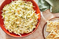 a red bowl filled with coleslaw next to crackers