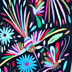 an embroidered piece of cloth with colorful flowers and birds on black background, closeup