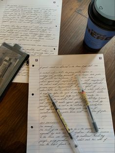 two pens on top of paper next to a coffee cup and pentagramt with writing on it