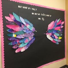 a bulletin board decorated with colorful feathers and writing on the back wall that says, but what if i fall?