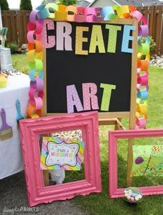 there are three frames on the grass with paper streamers all over them and one has a sign that says, create art