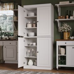 a kitchen with white cupboards and shelves in the corner, next to a window