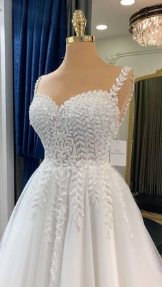 a white wedding dress on display in front of a mirror