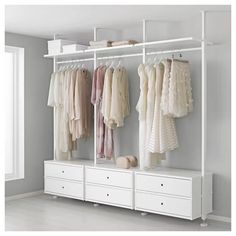 an organized closet with white drawers and hanging clothes