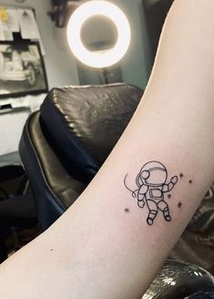 a small astronaut tattoo on the arm