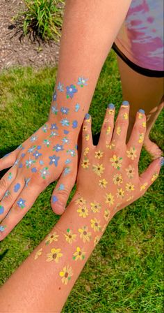 two hands with flowers painted on them and one hand holding the other's arm