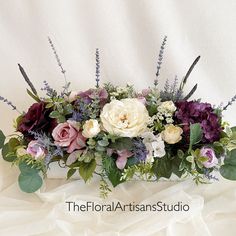 an arrangement of flowers and greenery on a white background