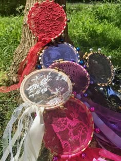 several different colored doily on the ground next to a tree