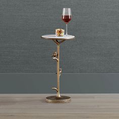 a glass of wine on a table with a gold metal stand holding a piece of food