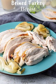 sliced turkey breast on a blue plate with pickles and potato chips next to it