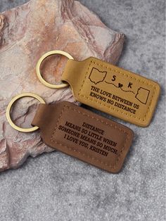 two leather keychains with the words, the love between us knows and distance