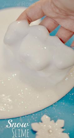 someone is making snow slime out of foam on a blue plate with white flowers