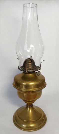 an antique brass oil lamp with a glass shade on it's top and base