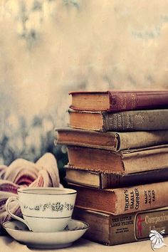 a stack of books sitting next to a cup and saucer