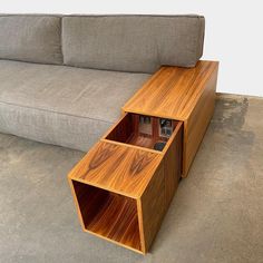 a couch and table in a room with concrete flooring, grey sofa behind it