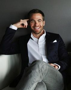 a man sitting on top of a white couch wearing a black jacket and white shirt