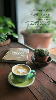 a cup of coffee sitting on top of a wooden table next to a potted plant