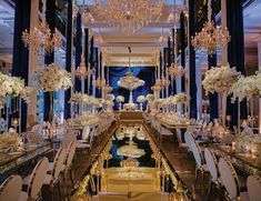 an elegant ballroom set up with chandeliers, tables and white flowers in vases